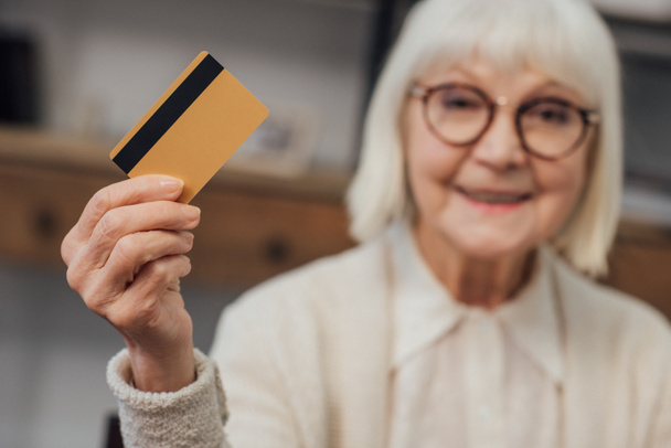selective focus of credit card in hand of smiling senior woman  - Foto, imagen