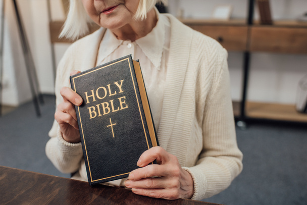 cropped view of senior woman holding holy bible at home - Valokuva, kuva
