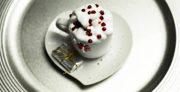 Christmas coffee with whipped cream and a small gift on ceramic saucer, xmas - Fotó, kép