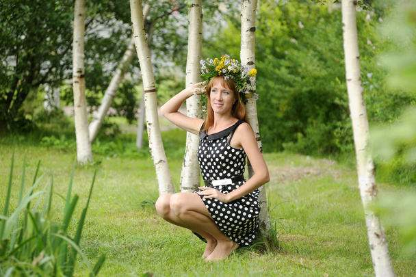 Woman wearing a crown of flowers next to a birch - Zdjęcie, obraz