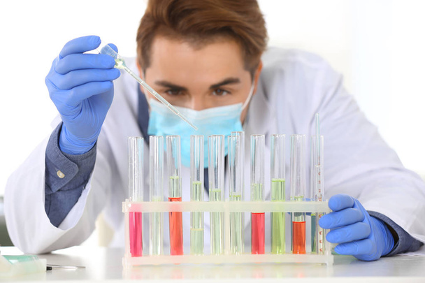 Αρσενικό επιστήμονας που δουλεύει σε εργαστήριο, εστίαση σε rack με σωλήνες δοκιμής. Έρευνα και ανάλυση - Φωτογραφία, εικόνα