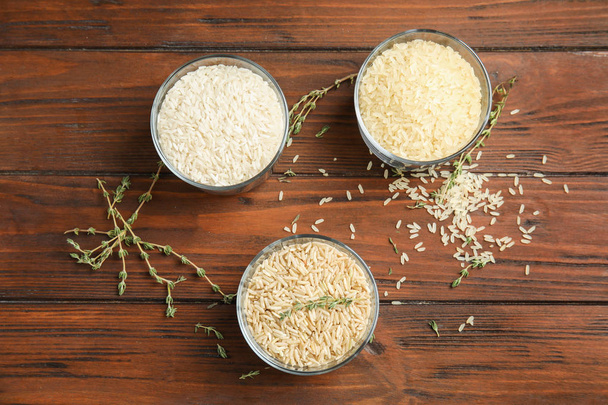 Glasses with different types of rice on wooden background, top view - Foto, afbeelding