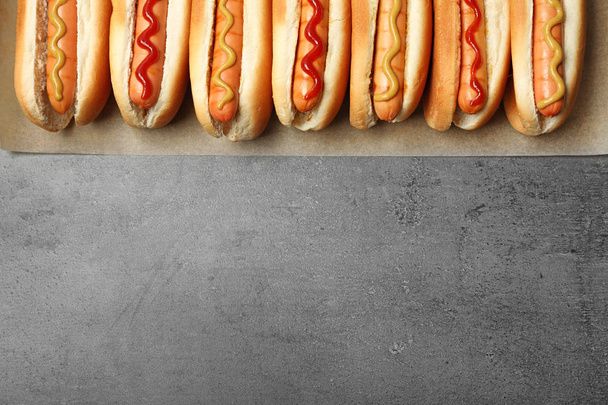 Tasty fresh hot dogs on grey background, top view. Space for text - Foto, imagen
