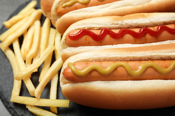 Delicious hot dogs and french fries on slate plate, closeup - Zdjęcie, obraz