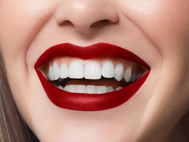 Γκρο πλαν πλάνο της σέξι γυναίκας χείλη με κόκκινο κραγιόν και καθαρό δέρμα. Όμορφο σπα πορτραίτο με ένα ολόλευκο χαμόγελο. Spa και καλλυντικά, οδοντιατρική και την κοσμετολογία, εξαγωγή δοντιών - Φωτογραφία, εικόνα