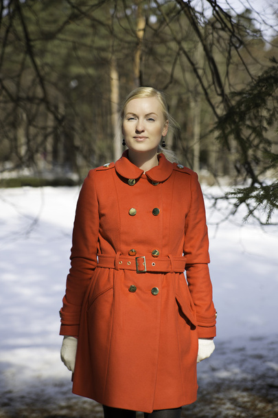 Молодая женщина в пальто позирует под елкой
 - Фото, изображение