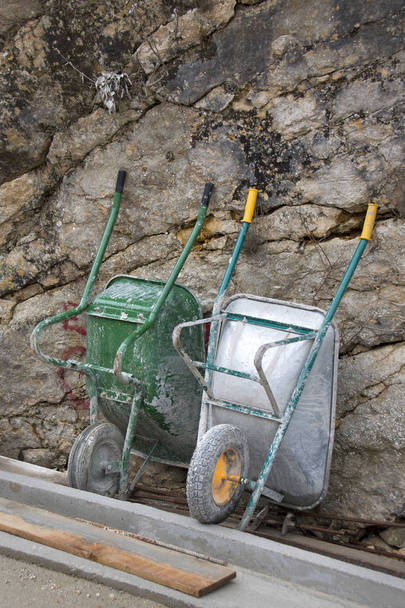 Due carte a una ruota vuote appoggiate sulla roccia solida in cantiere
 - Foto, immagini