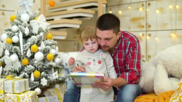 Caring father teaches toddler daughter to draw at Christmas time - Footage, Video