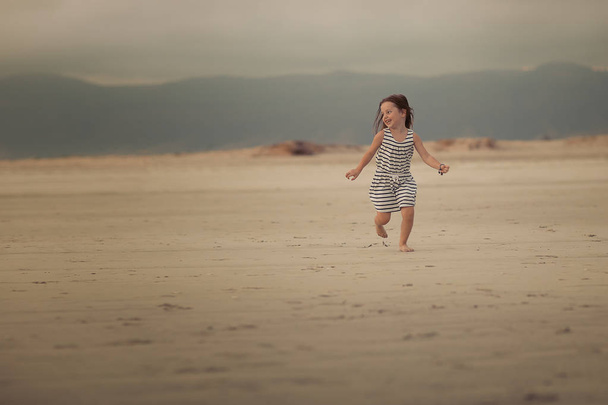 full length shot of happy girl running on the sandy beach  - 写真・画像