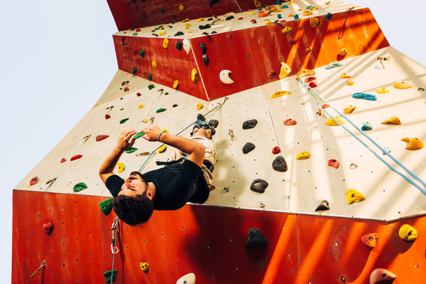 Sportovní horolezec sestupující na skalní lezení umělé stěny - Fotografie, Obrázek