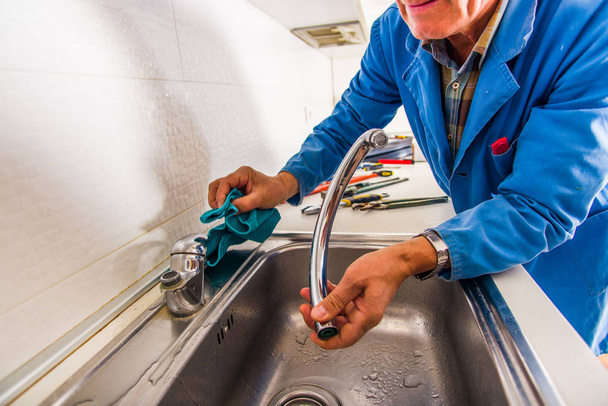 Old age handyman is fixing the broken kitchen faucet - Φωτογραφία, εικόνα