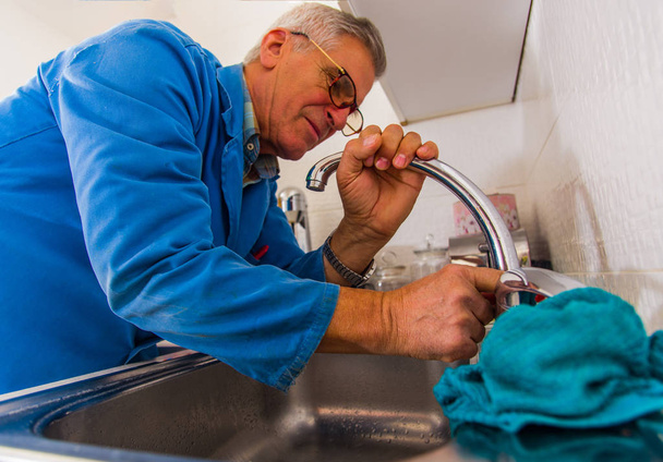 Reparador de velhice grave está consertando a torneira da cozinha
 - Foto, Imagem