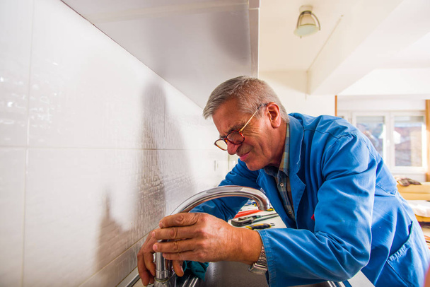 O faz-tudo profissional está consertando a torneira da cozinha com suas ferramentas
 - Foto, Imagem