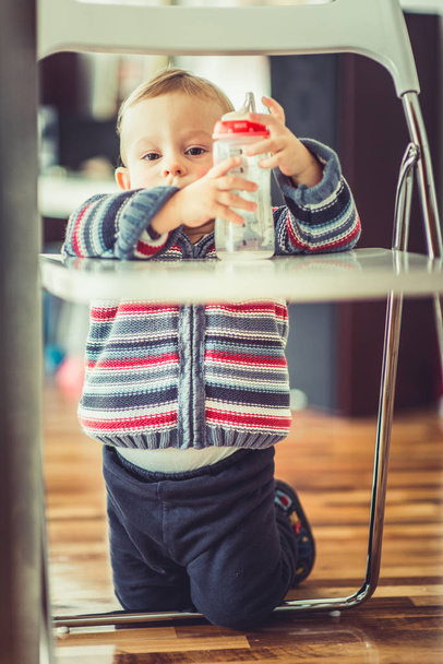 A beautiful baby is holding and looking in his empty bottle - Фото, зображення