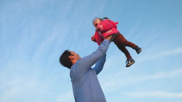Isä heitti vauvan siniselle taivaalle. Isä oksentaa vauvaa. onnellisen perheen käsite. Isä leikkii tyttärensä kanssa puistossa.
. - Materiaali, video