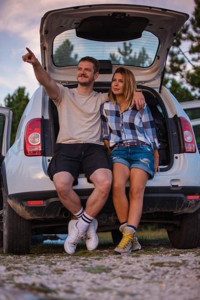 Fiatal pár ül a hátsó egy off-road jármű és élvezi a kilátást belülről az összes terepjáró naplementekor. - Fotó, kép