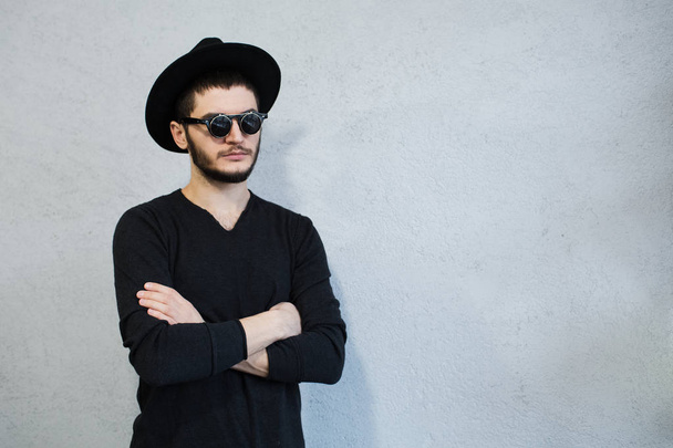Portrait of hipster man dressed in black with sunglasses and hat on white background - Foto, Imagen