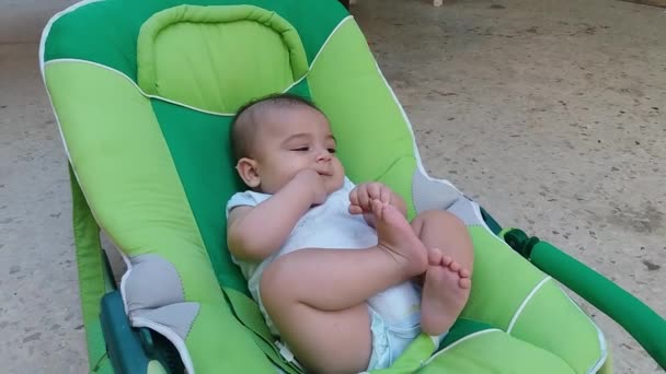 Kousací chlapeček v vyhazovač uvedení prsty do pusy a hrát si s nohama - Záběry, video