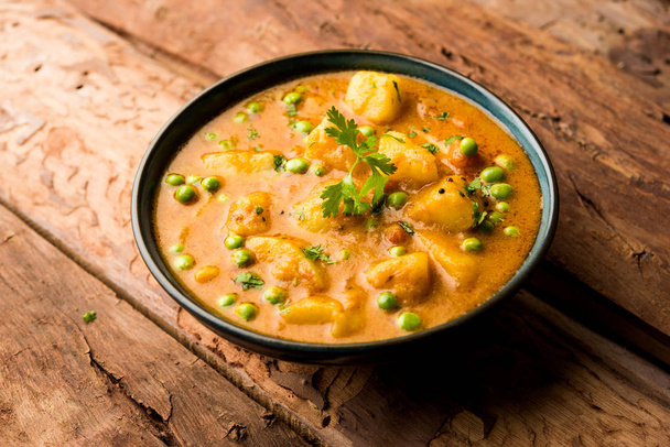 Indian Aloo curry Mutter - ziemniaki i groszek zanurzone w sosie pomidorowym cebula i przyozdobionym z liści kolendry. Serwowane w Karahi/kadhai lub patelni lub miski. Selektywny fokus - Zdjęcie, obraz