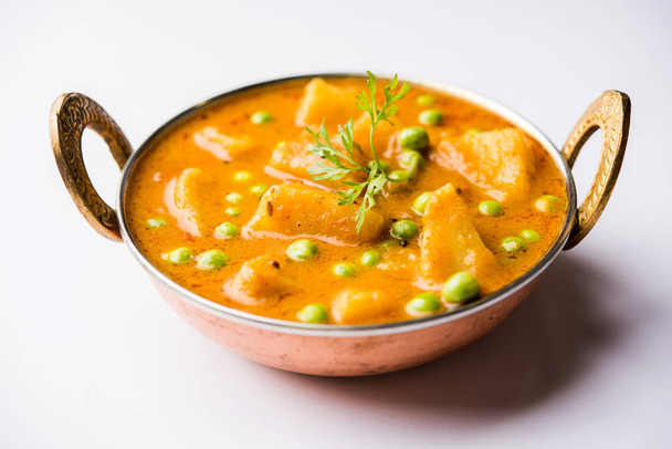 Indian Aloo Mutter curry - Batata e ervilhas imersas em um molho de tomate de cebola e decoradas com folhas de coentro. Servido em um Karahi / kadhai ou panela ou tigela. foco seletivo
 - Foto, Imagem
