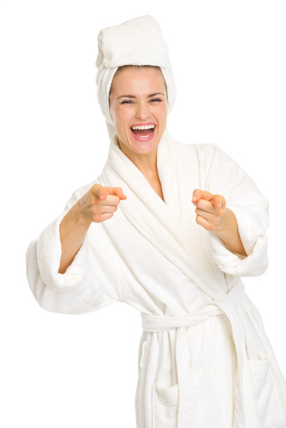 Happy young woman in bathrobe pointing in camera - 写真・画像