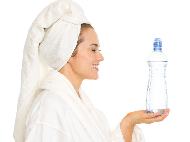Happy young woman in bathrobe holding bottle with water - Valokuva, kuva