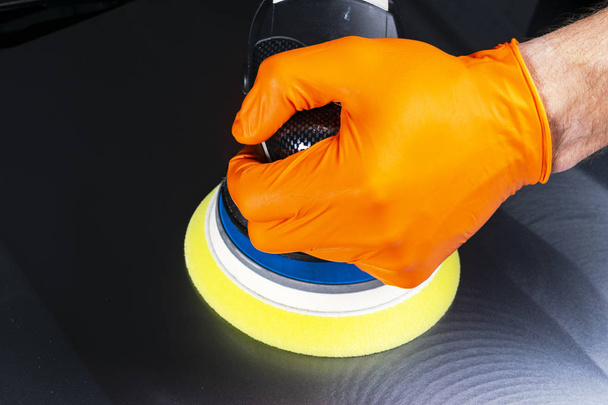 Car polish wax worker hands applying protective tape before polishing. Buffing and polishing car. Car detailing. Man holds a polisher in the hand and polishes the car. Tools for polishing - Фото, изображение