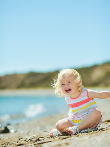 Happy baby girl playing with sand on beach - Fotografie, Obrázek