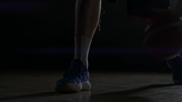 Dribbling basketball player close-up in dark room in smoke close-up in slow motion - Video