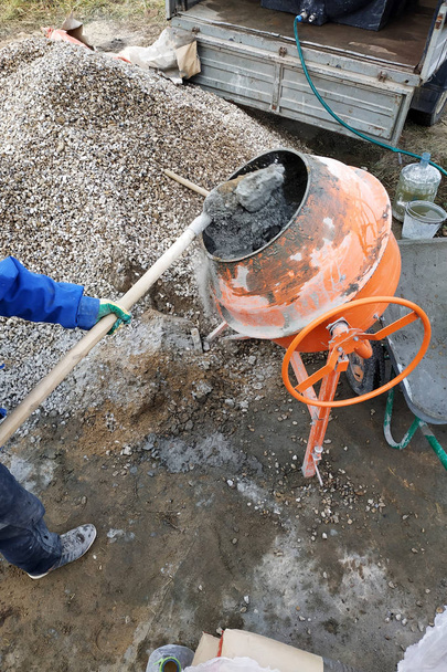 βοηθητική εργαζόμενος χρησιμοποιεί ένα φτυάρι να προετοιμάσει μια τσιμεντοκονία σε ένα εργοτάξιο 2018 - Φωτογραφία, εικόνα