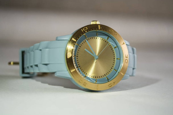 Zegarek na rękę kobiety z dial złoto i niebieski gumowy stringi. - Zdjęcie, obraz