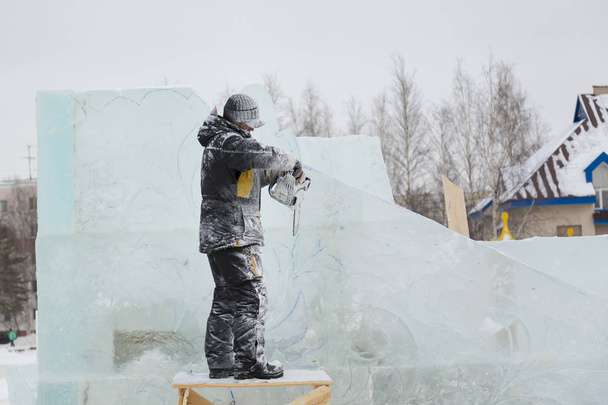der Bildhauer schneidet mit der Kettensäge Eiskonturen aus Eis für Weihnachten - Foto, Bild