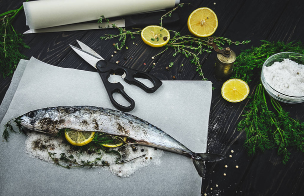 Свежая скумбрия с ингредиентами для приготовления: лимон, зелень и специи. Рыба-повар с травами
 - Фото, изображение