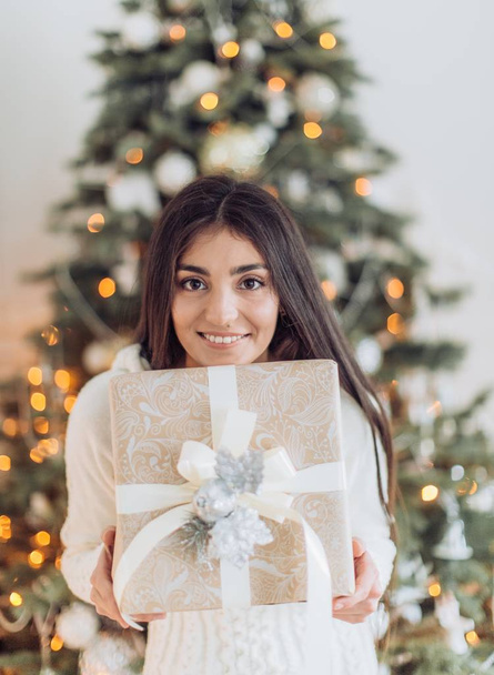 Szép nő, ajándék karácsonyfa jelentő otthon közelében  - Fotó, kép