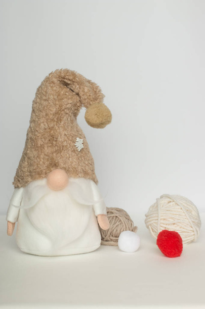 Beyaz elbise ve beyaz zemin üzerine yün topları ile sıcak bir şapka İsveç gnome - Fotoğraf, Görsel