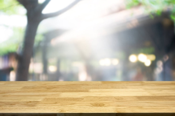 Порожній коричневий дерев'яний стіл і розмитий фон абстрактних ресторанних вогнів можна використовувати для монтажу або відображення ваших продуктів
.  - Фото, зображення