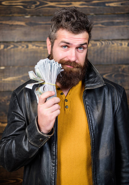 Guy mafia dealer with cash profit. Brutal man has cash money. Richness and wellbeing. Man brutal bearded hipster wear leather jacket and hold cash money. Mafia business. Illegal profit and black cash - Фото, изображение