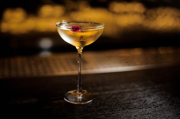Elegant cocktail glass filled with tasty sweet drink decorated with rose bud - 写真・画像
