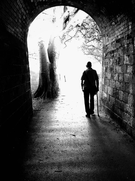 Into the Light.  Black and white shot of silhouetted figure walking into the light. - Photo, Image