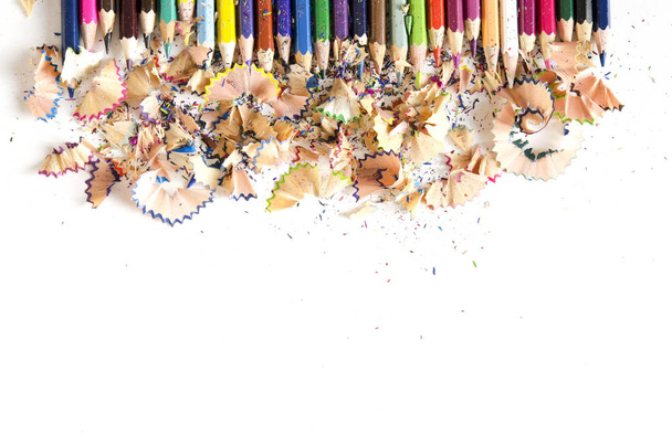 Outils de dessin fond. Beaucoup de crayons colorés encadrent avec de la sciure de bois et des copeaux sur blanc, espace de copie, pose plate
 - Photo, image