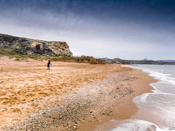 Rückansicht eines Jungen, der am Strand von Beton läuft, Griechenland, Europa - Foto, Bild