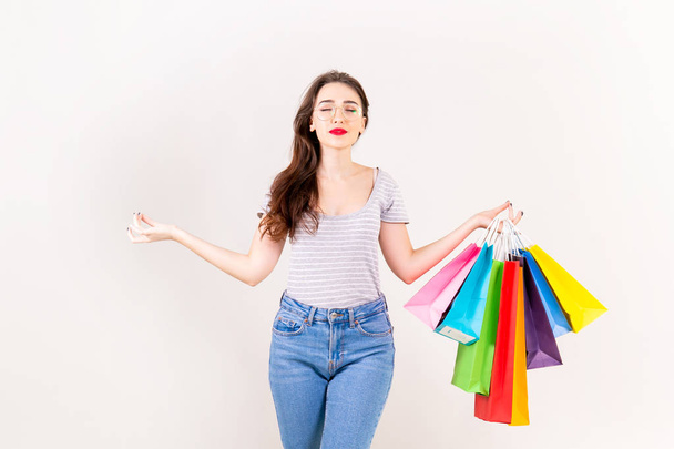 Spring summer season sale concept. Attractive young woman with long brunette hair, wearing slim fit casual shirt, holding many different blank shopping bags over white background. Copy space, close up - Fotoğraf, Görsel