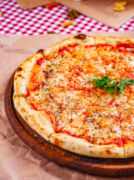 Italienische Pizza Margherita mit Tomaten und Mozzarella auf einem Holzschneidebrett. Nahaufnahme - Foto, Bild