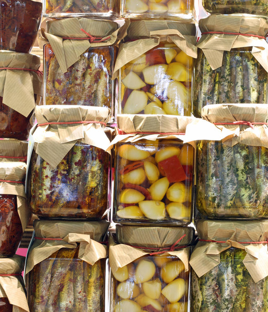 πολλά βάζα με σκελίδες σκόρδο με γαύρο μαρινάτο προετοιμάζονται με το χέρι σε μια μεσογειακή χώρα και πιπεριές - Φωτογραφία, εικόνα