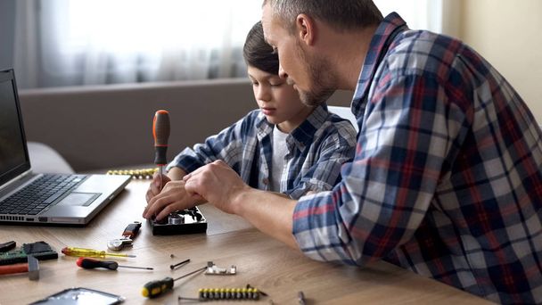 Caring father teaching his little son to repair hard disk drive at home, hobby - Photo, Image