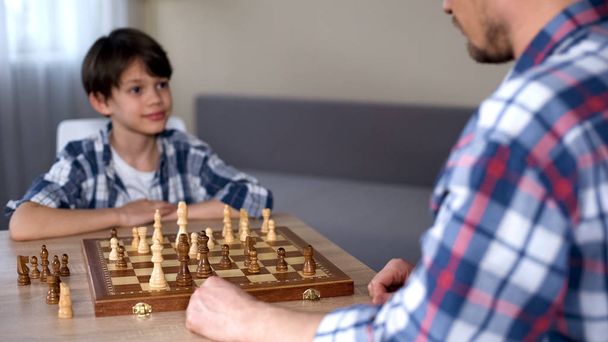 Little smart boy winning chess game, happily looking at father, favorite hobby - Foto, imagen