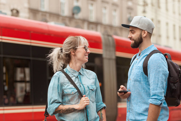 Young woman and man talking inthe city street, city train in the background.  - Foto, Imagen