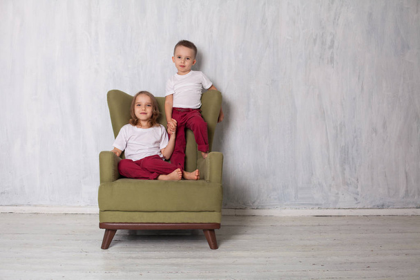 αγόρι και κορίτσι είναι αδελφός και αδελφή του κάθεται σε μια πολυθρόνα πράσινο - Φωτογραφία, εικόνα