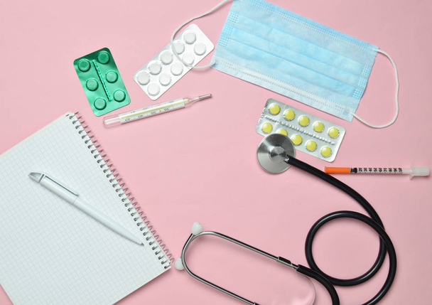 Attrezzature mediche su sfondo rosa pastello. Pillole per vesciche, blocco note, stetoscopio, termometro. Concetto medico, vista dall'alto, styl flat lay
 - Foto, immagini