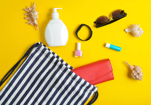 Strandtasche und Accessoires zum Entspannen am Strand auf gelbem Pastell-Hintergrund. das Konzept des Seebades, Sommerzeit. Draufsicht, flach, minimalistisch - Foto, Bild
